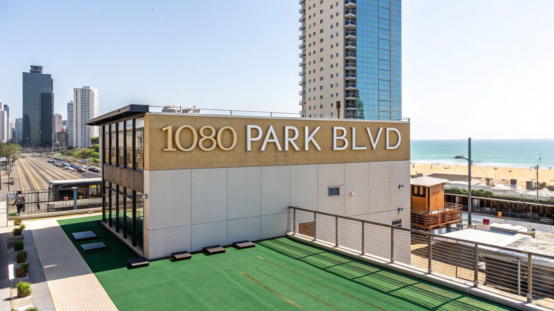 A rooftop area with green artificial turf is shown, featuring a large sign reading "1080 PARK BLVD." High-rise buildings, a beach, and Lake Michigan are visible in the background on a sunny day.