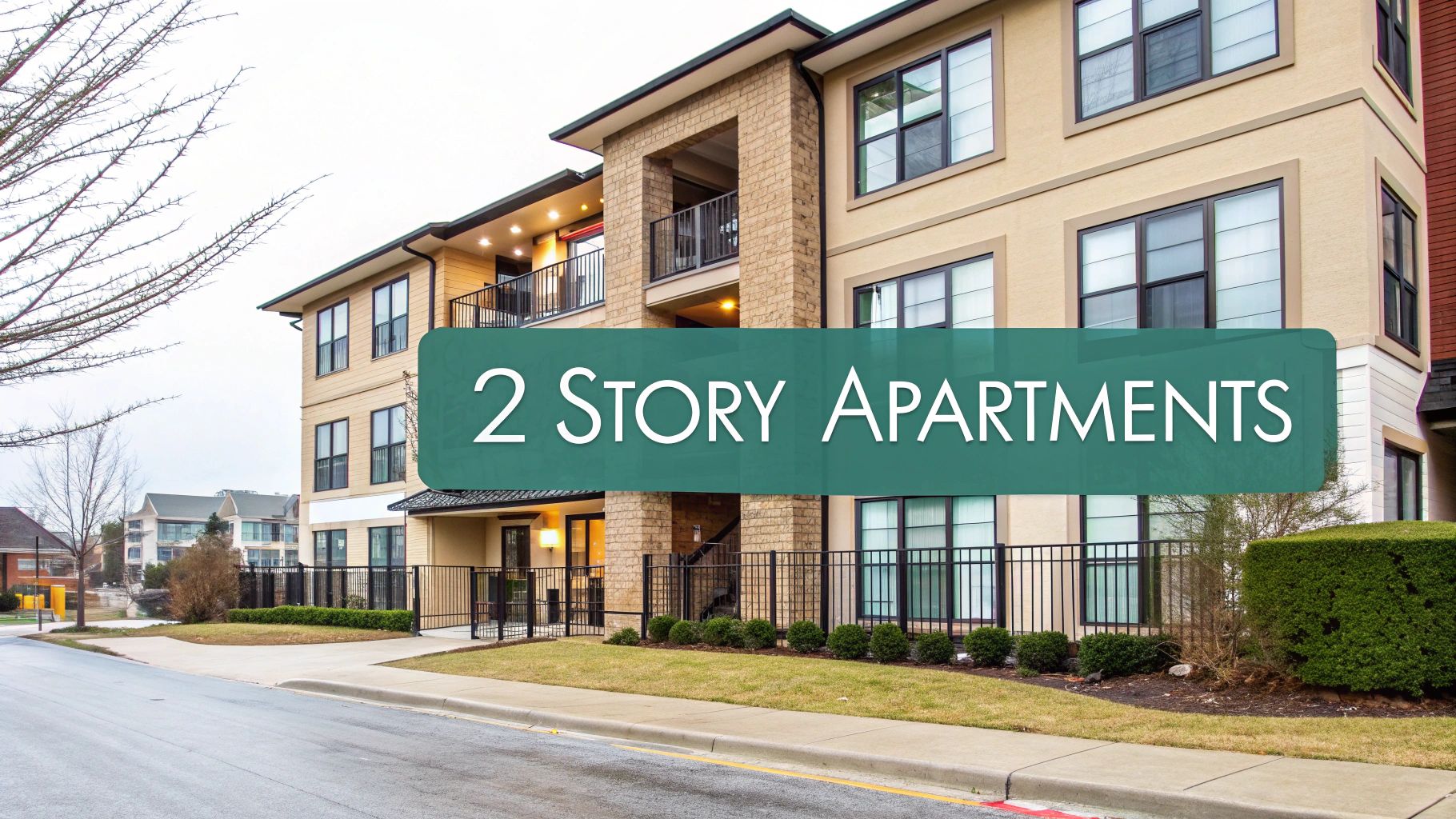A modern, beige two-story apartment building with balconies and large windows. A green sign in the foreground reads "2 Story Apartments." Shrubs and a sidewalk line the front of the building.