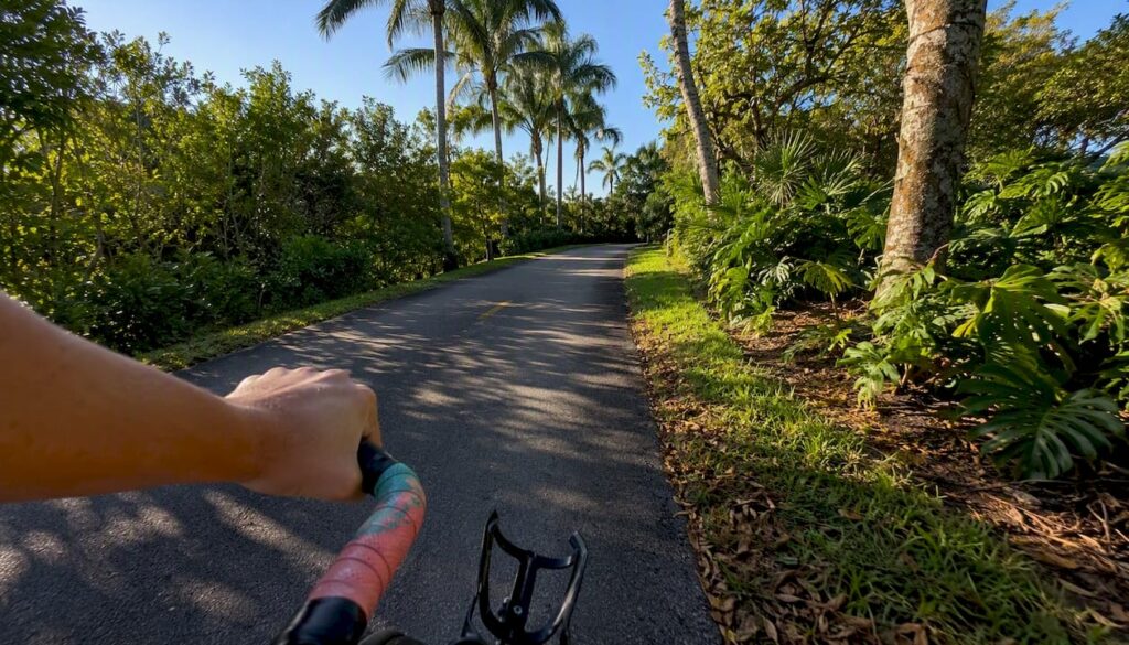 Shaded Boca Raton bike trail with partial bike handlebar