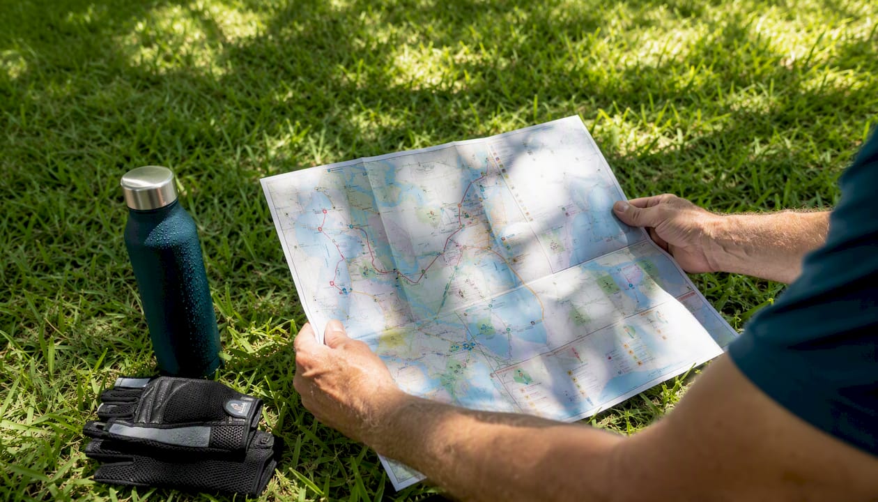 Best Bike Routes in Boca Raton: Your Complete Riding Guide 1 Hands unfolding printed Boca Raton bike map outdoors